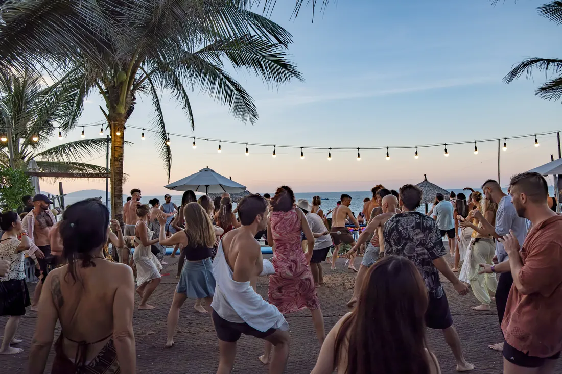 People gathered and dancing at golden hour on the beach
